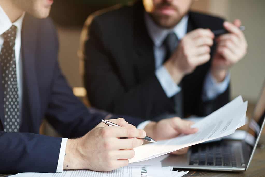 An image of two businessmen in suits discussing a document - an affidavit.