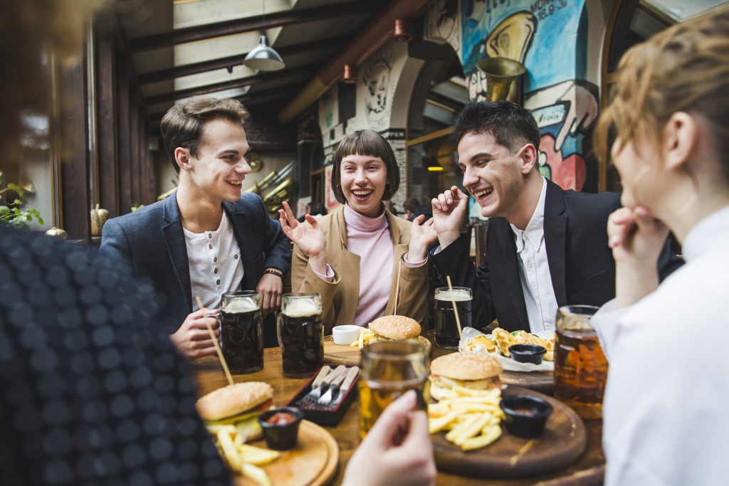A group of friends smiling and laughing over a meal in a restaurant.
